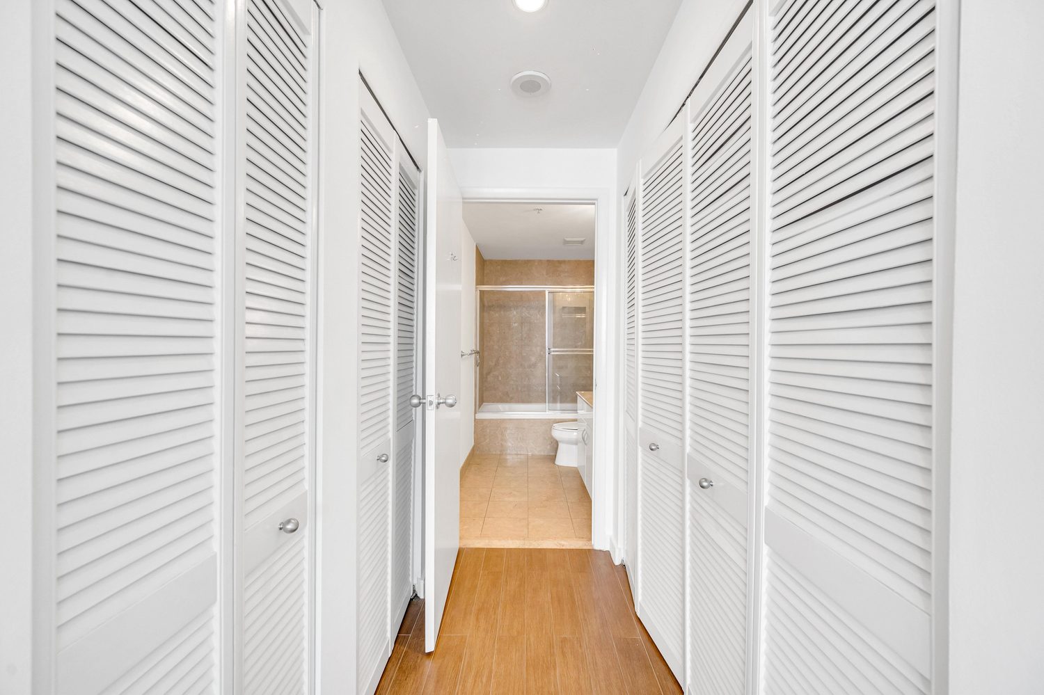 Hallway with closets leading toward the bathroom